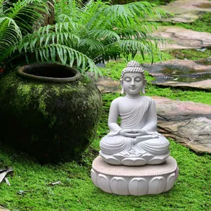 Zen garden Buddha statue detail showing white meditating Buddha figurine on lotus base.