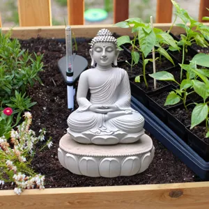 Close-up of a tranquil Buddha statue figurine nestled in garden soil, detail shot for decor.