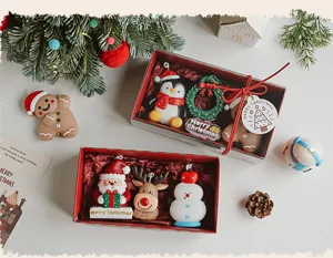 Christmas scented candle set detail view, cute holiday shapes like penguin and Santa in gift box.