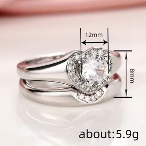 Vista detallada del anillo doble en forma de corazón con piedras brillantes y diseño elegante.