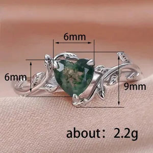 Vista detallada del anillo de ágata musgosa en forma de corazón con diseño de ramas.