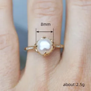 Detalle en primer plano del anillo de perlas, perla de 8mm con banda dorada y piedras, elegante.