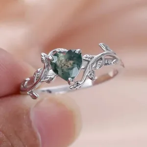 Primer plano detalle del anillo de plata con diseño de rama y piedra ágata musgo.