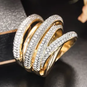 Nahaufnahme eines breiten, mehrreihigen Kristallrings mit funkelndem geometrischem Crossover-Design.