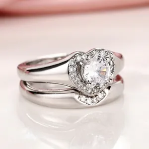 Detalle del conjunto de anillos de corazón entrelazados con piedras brillantes y acabado plateado.