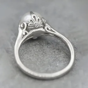 Primer plano detallado del anillo de perlas vintage con intrincado diseño plateado.