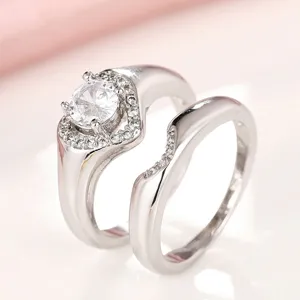 Impresionante juego de anillos de pareja plateados con un brillante diseño de halo.