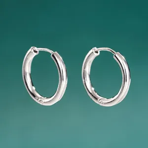 Primer plano detallado de pendientes de aro redondos lisos minimalistas, estilo de superposición.