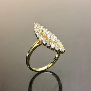 Detalle en primer plano de un precioso anillo dorado de racimo con circonitas brillantes.