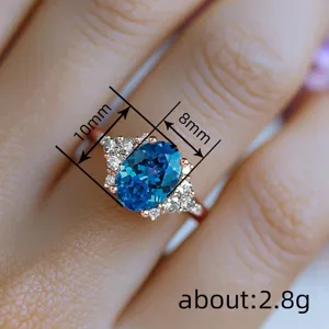 Ocean style oval synthetic sapphire ring with crystal cluster side stones and rose gold band.