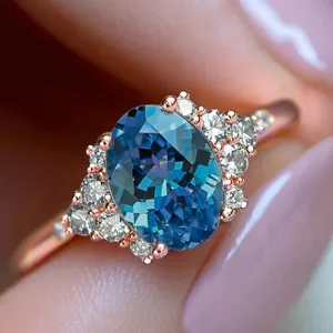 Close-up detail of luxury oval blue gemstone ring with sparkling crystal cluster in rose gold.