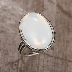 Vintage silver ring with large oval white opal gemstone and dark side textures detail.