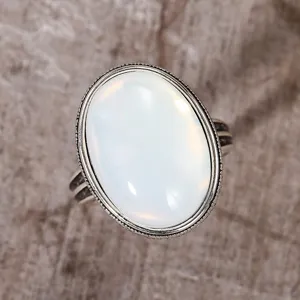 Close-up of vintage oval synthetic moonstone ring with textured blackened silver detail.