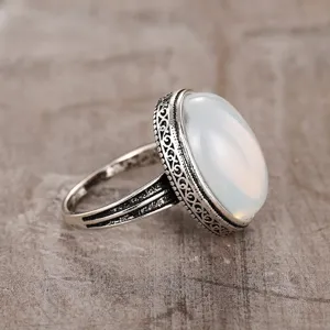 Close-up detail of the retro oval translucent stone ring showing ornate filigree texture.