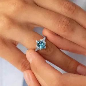 Primo piano dettagliato dell'elegante anello con pietra blu e zirconi scintillanti.