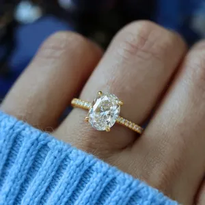 Elegante anillo de compromiso ovalado en oro amarillo con piedras brillantes pavé.