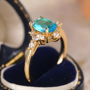 Primo piano dell'anello in oro con pietra ovale blu brillante e zirconi scintillanti.
