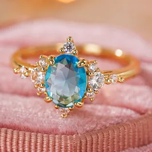 Anello placcato oro stile oceano con gemma blu ovale e dettagli di zirconi luminosi raffinati.