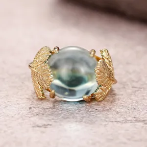 Primer plano detallado del elegante anillo dorado de hoja de ginkgo con piedra transparente.