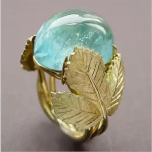 Vista detallada del elegante anillo de cabujón azul con detalles de hojas doradas.
