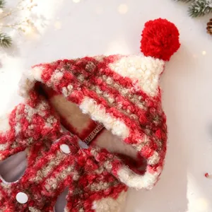 Close-up detail of festive red and white pet Christmas cape with fluffy hood and pom-pom.