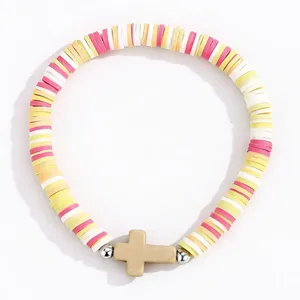 Gros plan sur le bracelet en perles d'argile polymère colorées avec pendentif croix tendance.