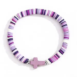 Vue detaillee d'un bracelet tendance en perles d'argile heishi avec un pendentif croix violet.