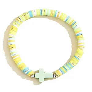 Gros plan du bracelet de perles en argile polymère bohème avec un pendentif croix.