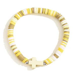 Gros plan du bracelet en perles d'argile colorées avec une croix élégante et un cordon élastique.