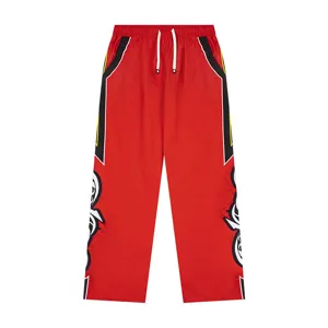 Red streetwear track pants side tribal embroidery detail casual athletic trousers close-up