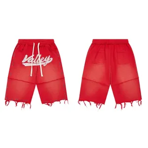 Detailed view of red streetwear shorts featuring rhinestone script text and distressed frayed hems.