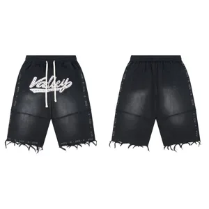 Detailed view of black washed denim shorts with rhinestone Valley letters and raw hem.
