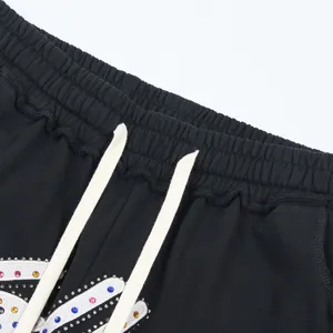 Detailed view of black casual shorts featuring a white drawstring and colorful rhinestones.