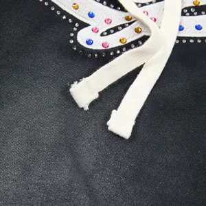Detailed shot of black washed fabric apparel featuring colorful rhinestones and embroidery.