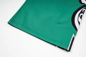 Close-up detail of casual pants hem showing contrast color embroidery and neat stitching.
