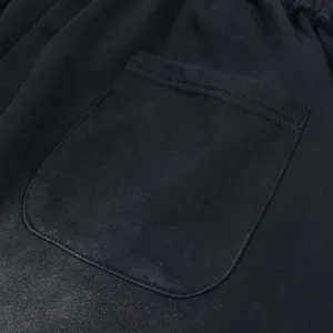Close up detail shot of casual shorts back pocket, showing fine stitching and washed black fabric.