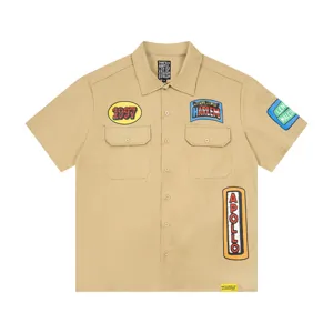 Casual khaki short-sleeve work shirt featuring stylish graphic patches, lapel collar, and button front.