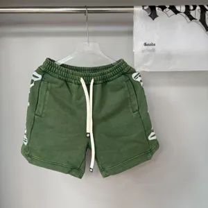 Dettaglio dei pantaloncini streetwear vintage verde lavato con ricamo gotico bianco laterale.