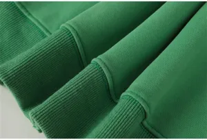 Close up view of green hoodie fabric and ribbed cuff, showing premium texture and quality.