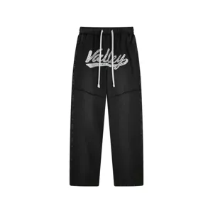 Λεπτομερής όψη μαύρου streetwear παντελονιού φόρμας με κέντημα γραμμάτων από στρας και κορδόνι.