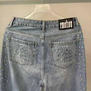Distressed light blue denim jeans featuring rhinestone sides and gothic embroidered back pockets.