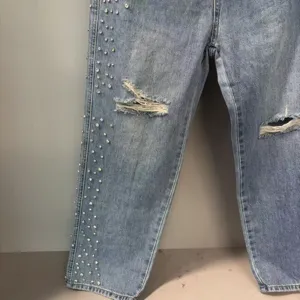 Distressed light wash denim jeans featuring rhinestone embellishments and cool ripped knees.