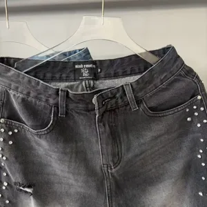 Close-up of grey washed denim jeans with rhinestone embellishments and distressed details.