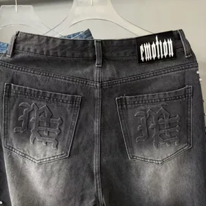 Distressed washed black denim jeans featuring gothic brand text and back pocket embroidery.