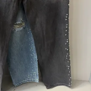 Detailed view of high-street contrast wash ripped jeans with rhinestone side embellishments.