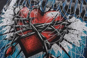 Detailed view of washed vintage streetwear t-shirt with rhinestone heart and gothic graphic.