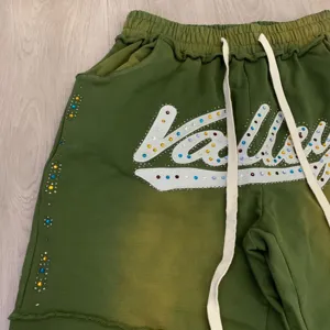 Λεπτομέρεια πράσινου παντελονιού φόρμας streetwear, λογότυπο με στρας, vintage στυλ.