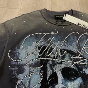 Detailed view of the washed dark gray short sleeve t-shirt with rhinestone letter graphics.