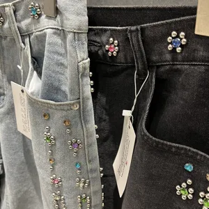 Close-up detail of rhinestone studded denim shorts, showing sparkling crystal flower decorations.