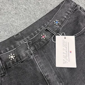 Close-up detail of washed denim shorts waistband featuring colorful rhinestone crystal studs.